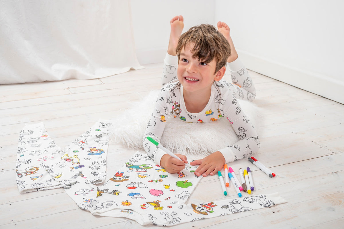 A child coloring his farm animal pajamas with fabric markers