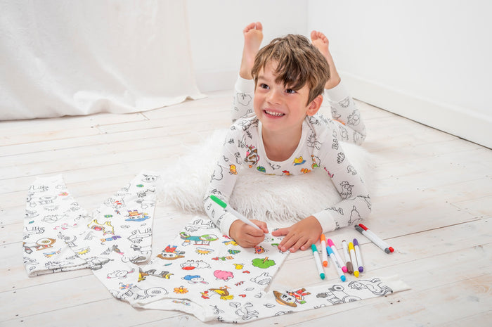 A child adding color to his farm animal pajamas